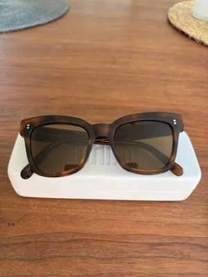 Chimi solglasögon - Snygga solglasögon från Chimi med fyrkantig form och klassiskt brunt sköldpaddsmönster. Glasen är mörka och bågarna är tillverkade i ett syntetmaterial. Perfekt för att höja din stil under soliga dagar. Har lite repor på glaset