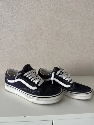  Vans Old Skool sneakers - Klassiska Vans Old Skool sneakers i mörkblått mocka och canvas med vita detaljer och vit sula. Skorna har den ikoniska vita sidan, vita skosnören och låg profil. Det är bara höra av sig vid frågor!  Mvh freddysgarderob