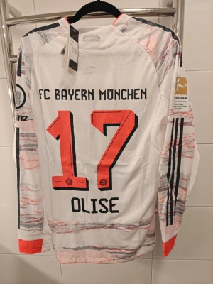 Bayern München långärmad matchtröja spelar Version  - Säljer en långärmad spelar Version Bayern München matchtröja från Adidas med nummer 17 och namnet Olise på ryggen. Tröjan är vit med röda och grå detaljer, svarta ränder på ärmarna och officiella Bundesliga-märken. Perfekt för fotbollsfans!