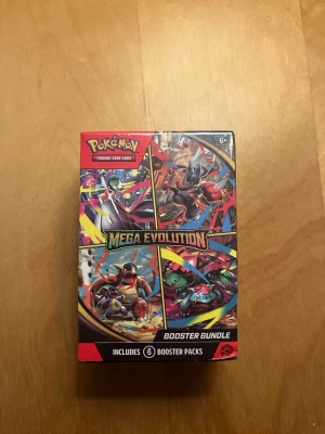 Pokémon Mega Evolution Booster Bundle - Pokémon Mega Evolution Booster Bundle med 6 booster packs. Färgglad rektangulär ask i kartong med motiv av olika Pokémon och texten Mega Evolution. Perfekt för samlare och fans av Pokémon Trading Card Game. (Obs ej original).