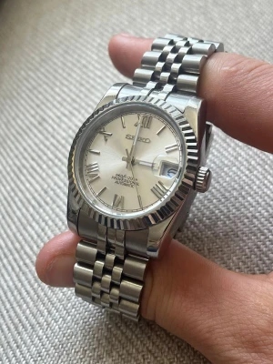Seiko Mod - Seiko Mod Klocka,  storleken är 36 mm utan kronan och runt 39 med kronan, Omrketsen är ungefär 17 cm, sitter väldigt tight på mig som är 18.5 cm. Det är en NH35 vilket sägs vara automatisk, men vet ej hur bra den automatiska uppdragningen är, den går iaf också att veva upp.  Inga defekter, i nyskick. Armbandet går är ganska stretchy så den kan passa lite mer / mindre än 17 cm. 