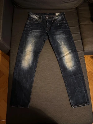 G-Star RAW 3301 mörkblå jeans - Säljer ett par G-Star RAW 3301 jeans i mörkblå tvätt med slitna detaljer och snyggt blekta partier på benen. Lite tapered look.