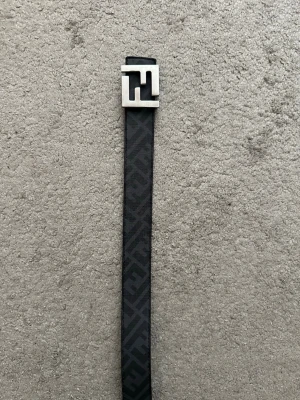 Svart Fendi bälte med silverfärgat spänne - Snyggt svart bälte från Fendi med klassiskt FF-mönster och ett stilrent, silverfärgat spänne. Bältet är gjort i skinn och har en exklusiv känsla som lyfter vilken outfit som helst.