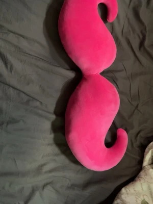 Rosa mustasch-kudde från Flying Tiger - Säljer en unik och rolig kudde formad som en stor rosa mustasch från Flying Tiger. Kudden är gjord i mjukt plyschmaterial och har en stark rosa färg. Perfekt som dekoration i soffan eller på sängen för dig som gillar färgglada detaljer.
