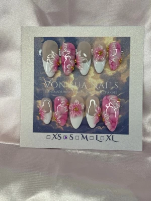 Rosaline (S);Medium Almond - Handgjorda press-on naglar i en medium lång almondform. Designen har en nude bas med vita french tippar och handgjorda 3D-blommor i rosa och vitt, dekorerade med små gulddetaljer. Perfekt för dig som vill ha en unik och kreativ look på naglarna.S: 15 mm, 11,5 mm, 12 mm, 11 mm, 9 mm 