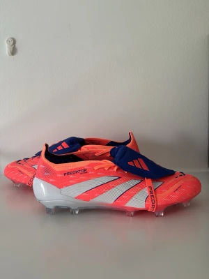 Adidas Predator CORAL BLAZE  Elite  - Säljer ett par Adidas Predator fotbollsskor i en riktigt snygg rosa färg med vita och blå detaljer. Skorna har klassisk låg profil, snörning med blått skyddslock och mönstrad ovandel för extra grepp. Perfekta för dig som vill sticka ut på planen.