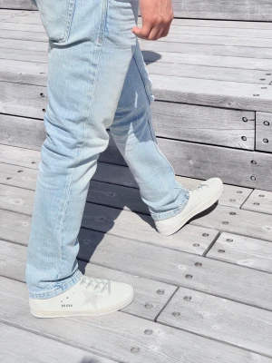 Golden Goose - Snygga vita sneakers från Golden Goose med silverfärgade detaljer, grå snörning och den ikoniska stjärnan på sidan. Skorna har en låg siluett och är tillverkade i läder med slitna detaljer för en cool look.