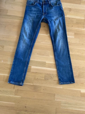 Blå raka jeans i klassisk modell - Säljer ett par blå jeans med raka ben och klassisk femficksmodell. Jeansen har snygga slitningar och kontrastsömmar. Tillverkade i slitstark denim som ger en tidlös look. Perfekta för dig som gillar en enkel och stilren stil.