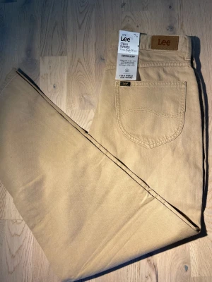  Lee Stellar Tapered jeans - Säljer ett på Lee Stellar Tapered jeans i färgen beige. Jeansen är helt nya och aldrig använda. De är ehh par jeans som är gjort av bra material och som passar till alla outfits.
