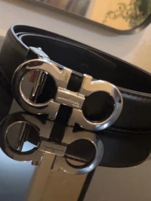 Ferragamo Gancini  - Stilrent silver skärp från Salvatore Ferragamo med ikoniskt dubbel-Gancini-spänne i metall. Skärpet är gjort i slätt skinn och har en elegant, tidlös design som passar till många olika outfits.