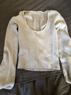 Beige ribbad långärmad topp - Trendig beige ribbad topp med lång ärm och djup rundringning. Croppad modell som passar perfekt till jeans eller kjol. Mjuk och stretchig i materialet för en bekväm passform.