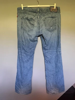 True Religion jeans - Snygga true religion jeans som tyvärr är för stora för mig. Har en snygg wash och tag som jag aldrig sett innan ibak! Mått: Midja rakt över, 54cm. Längd, 108cm. Benöppning: 25cm. Hör av dig vid fler frågor!! 
