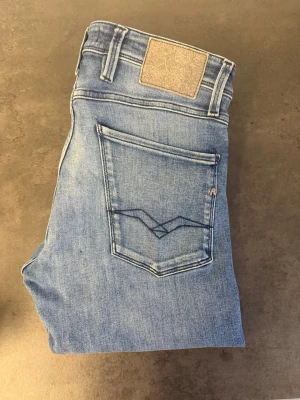 Blå slim jeans från Replay stl 32/36 - Snygga ljusblå jeans från Replay i slim fit-modell. Klassisk femficksdesign med dragkedja och knapp framtill. Tillverkade i mjuk bomull med lite stretch för extra komfort. Perfekta till en avslappnad look.