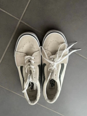 Vans vita sneakers – Low Top | Mycket fint skick - Snygga vita Vans Old Skool sneakers med klassisk svart sidorand. Skorna har ovandel i canvas och mocka, vita snören och gummisula med svart rand. Perfekta för en avslappnad streetstil.