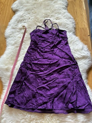 Lila klänning i sidenlook - Snygg lila klänning med glansig sidenkänsla. Tyget har ett mjukt fall och ger en elegant look. Perfekt för dig som vill sticka ut med färg och stil.
