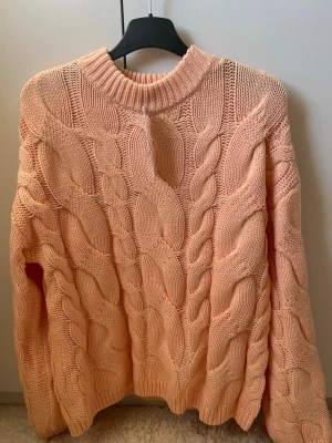 Chunky stickad tröja i aprikos - Chunky stickad tröja från Gina tricot i en mjuk aprikos färg. Tröjan har grovt kabelstickat mönster, rund halsringning och långa ärmar. Perfekt för lager-på-lager och en mysig look. Materialet är akryl och polyester. Denna tröja är helt perfekt till lite kyligare sommarkvällar nu framöver. Eller bara att ta på sig dom sommar dagar tempen sjunker lite då den peppar upp dagen med sin otroliga färg!🧡🩷