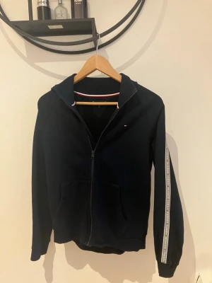 Marinblå hoodie från Tommy Hilfiger - Snygg Tommy hilfiger hoodie. Skön att ha på sig under sommaren! Priset är inte hugget i en sten så sätt din bud så diskuterar vi😁