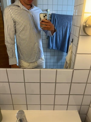 Blårutig skjorta från Massimo Dutti - Säljer en stilren blårutig skjorta från Massimo Dutti i slim fit-modell. Skjortan har långa ärmar, klassisk krage och knappar framtill. Tillverkad i mjuk bomull som känns skön mot huden. Perfekt för dig som gillar en clean och fräsch look.