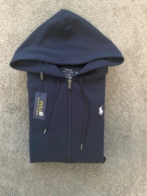 Polo Ralph Lauren Zipper - Snygg marinblå hoodie med dragkedja från Polo Ralph Lauren. Storlek M men passar mer som S. Perfekt för en avslappnad och stilren look. 