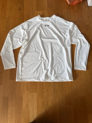 Vit oakley compression shirt - Vit långarmad compressionshirt - tänk på att det är storlek L och kräver att man är stor för att få compression fit.