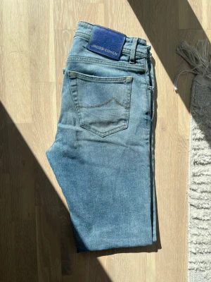 Ljusblå jeans från Jacob Cohen - Snygga ljusblå jeans från Jacob Cohen med klassisk femficksdesign och diskreta kontrastsömmar. Jeansen har en patch i blå mocka baktill och är tillverkade i mjuk denim med en något smal passform. Perfekta för en avslappnad och trendig look.