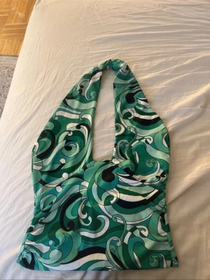 Grön mönstrad halterneck topp - Snygg halterneck topp med grönt, svart och vitt virvlande mönster. Toppen har djup urringning och knyts i nacken. Perfekt för dig som gillar färg. Perfekta sommar toppen!