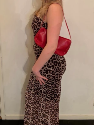Leopardmönstrad långklänning - Snygg leopardmönstrad tajt långklänning. Klänningen har smala axelband. Det är ett svart tyg under leopardtyget. Materialet är stretchigt. Jag är 178cm och klänningen slutar ca 10cm över mina fötter. Märket är noisy may men köpt på Vera Moda. Andvänt 1 gång! 