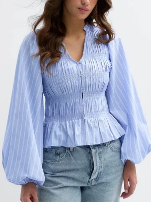 Ljusblå blus med puffärmar från Gina Tricot - Trendig ljusblå blus med vita ränder, smockad överdel och volang nertill. Blusen har långa puffärmar och knappar framtill. Perfekt för dig som gillar en romantisk och cool stil. Tillverkad i ett lätt och luftigt tyg.