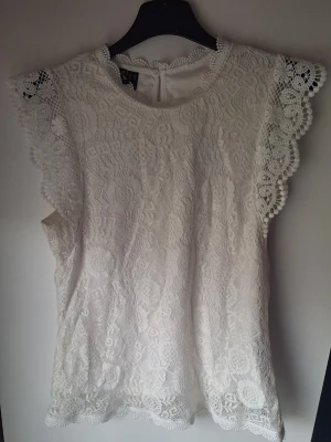 Vit spetsblus från Pieces - Superfin vit blus från Pieces i storlek XS. Blusen är ärmlös med vackra spetsdetaljer och rund halsringning. Kan ha lite trådar från spetsen som sticker ut men inget som märks💞