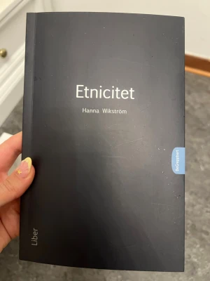 Etnicitet av Hanna Wikström - Kurslitteraturboken 'Etnicitet' av Hanna Wikström från Liber. Boken har ett stilrent svart mjukpärm-omslag med vit text och en blå flik på sidan. Perfekt för dig som pluggar samhällsvetenskap eller liknande ämnen.