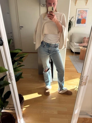 Ljusblå ripped jeans med hål - Säljer ett par ljusblå jeans med raka ben och stort hål på ena knät. Jeansen har klassisk femficksdesign och hög midja. Perfekta för en avslappnad och trendig look. Materialet är denim i bomull.