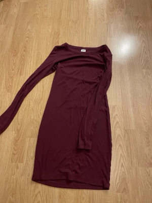Vinröd långärmad klänning Gina Tricot - En enkel och stilren vinröd klänning från Gina Tricot med lång ärm och rund halsringning. Klänningen är figurnära och har en kort längd, perfekt för dig som gillar en clean look.