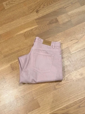 Ljusrosa raka jeans från Monki - Säljer ett par ljusrosa jeans från Monki med rak/wide passform och klassiska fickor bak. Jeansen har bälteshällor och är tillverkade i bomull. Perfekta för dig som vill ha en färgklick i garderoben!