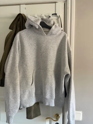 Grå hoodie från Gina Tricot - Säljer en ljusgrå hoodie från Gina Tricot, basically basics-kollektionen. Hoodien har en klassisk huva, magficka och ribbade muddar vid ärmslut och nederkant. Tillverkad i mjukt och skönt material, perfekt för chill dagar.