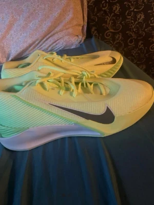 Nike limegröna sneakers - Säljer ett par riktigt snygga limegröna Nike sneakers med svart swoosh på sidan. Skorna har en sportig och modern design med meshmaterial för bra ventilation och en vit sula som ger schysst kontrast. Perfekta för dig som vill sticka ut med färg och stil.