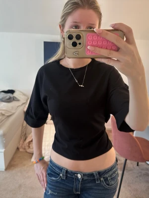 Svart knyt topp - Säljer en svart knyt topp från Nelly med rund hals och korta ärmar. Toppen har en enkel och stilren design som passar perfekt till jeans eller kjol. Materialet känns mjukt och bekvämt mot huden.