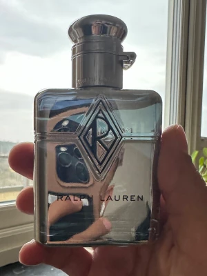Ralph Lauren Club New York 60 Ml - Flaska är använd fåtal gånger men lukten är otroligt bra och projection är mer än 8 timmar håller mer än 12 timmar.Snygg parfym från Ralph Lauren i en stilren, rektangulär flaska med spegelblank silverfinish och blå ton. Flaskan har ett stort RL-emblem på framsidan och metallock. Perfekt för dig som gillar exklusiva dofter och elegant design.