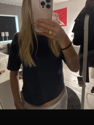 Mörkblå croppad t-shirt - En enkel och stilren mörkblå croppad t-shirt med rund hals och korta ärmar. Perfekt till jeans eller kjol för en avslappnad look. Materialet ser ut att vara mjukt och stretchigt, vilket gör den bekväm att bära.
