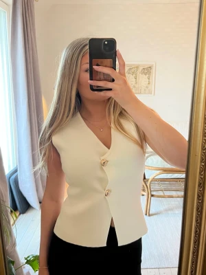 Vit topp från Zara - Vitt/offwhite topp med guldknappar från Zara, helt oanvänd med prislappar på.