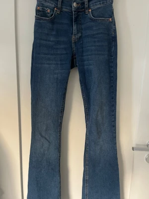 Blå bootcut jeans ifrån Gina tricot  - Säljer ett par klassiska blå bootcut jeans med mid waist. Dem är ifrån Gina tricot och är i storlek 32. Dem har lite slitningar på innerbenet se bild 3 men det är inget som syns när dom används 