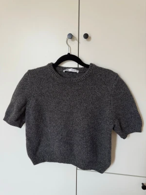 Stickad Zara topp, perfect skick - Säljer denna supersnygga gråa stickade topp från Zara perfekt för vår/sommar! Den är i stl L men har en mindre passform och passar dig som är runt S. Toppen är endast använd ett par gånger och därför İ perfekt skick!! Toppen slutar precis över naveln på mig💕