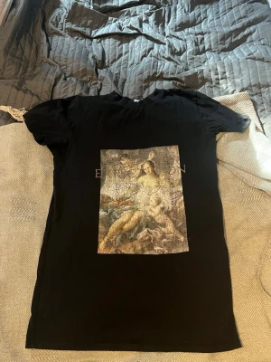 Svart t-shirt med konsttryck - Cool svart t-shirt med ett stort konstmotiv på framsidan. T-shirten har korta ärmar och passar både som en vanlig t shirt men och som en klänning.