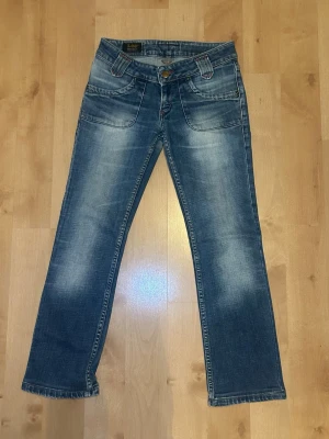 Blå bootcut jeans från Lee - Väldigt snygga lågmidjade bootcut jeans från Lee med coola guld-lika knappar på bakfickorna!⭐  Storlek: W28 W31 (S,36-ish). Innerbenslängd: 70 cm Midjemått: 36 cm  Jag är 170 cm lång, så dessa var lite för korta för mig, men dessa skulle sitta perfekt på någon mellan 160–166 cm.  De är i väldigt gott skick, och mycket litet slitna, förutom att den vänstra bakfickans knapp har lossnat.  Dessa Lee jeans består av material som är mycket uthärdigt och starkt!