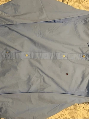 Blå skjorta Tommy Hilfiger S - Säljer en blå skjorta från Tommy Hilfiger i slim fit stretch. Klassisk design med knappar framtill och diskret logga på bröstet. Perfekt till jeans eller chinos för en clean och stilren look.