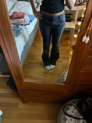 Mörkblå bootcut jeans - Snygga mörkblå bootcut jeans med klassisk femficksdesign och låg midja. Jeansen har en figurnära passform upptill och utsvängda ben. Perfekta för en trendig och avslappnad stil.
