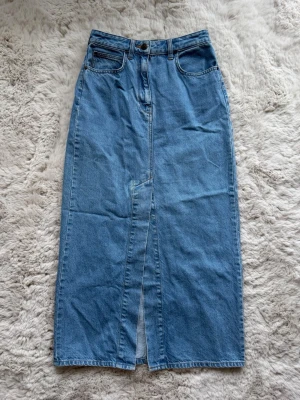 Lång jeanskjol Lee - Ljusblå lång jeanskjol med öppning framtill ⭐️ liten lagning framtill men ingenting som syns mycket, liten färgförändring baktill längs midjan. Glider runt på mig som är 34 så skulle tippa 36-38 passar ⭐️