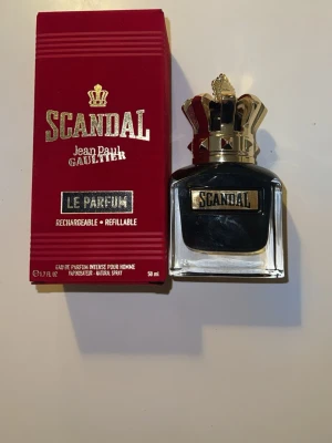 Scandal Le Parfum Jean Paul Gaultier - Scandal Le Parfum från Jean Paul Gaultier är en lyxig herrparfym i en elegant glasflaska med svart och guld detaljer. Flaskan har en unik kronformad guldkork och etikett i guld. Förpackningen är röd med guldtext och parfymen är på 50 ml. Ungefär hälften kvar.