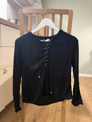 Svart topp H&M - Svart topp H&M storlek 38. Men liten i storlek. Toppen har trekvartsärm och har snörning. Har ett svart linne och kjol. Annars är de rätt tunt tyg (se bild 4) oanvänd.