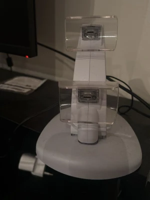 Laddningsstation för Ps5 kontroller  - Snygg vit laddningsstation med plats för två Ps5-handkontroller. Har USB-C-portar och transparenta hållare i plast. Perfekt för att hålla ordning och ladda dina kontroller samtidigt. Passar bra på skrivbordet eller vid TV:n.