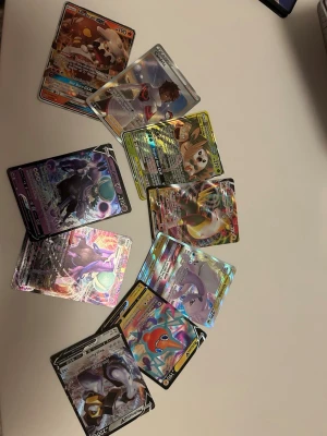 Pokémon GX och V samlarkort - Ett gäng Pokémon samlarkort med GX och V-kort, flera med holografisk yta och färgglada motiv. Bland korten finns populära Pokémon och tränare, perfekta för samlare eller Pokémon-fans som vill utöka sin samling.